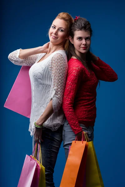 Back-to-back shoppers exude cheer, their shopping success displayed in vivid bags