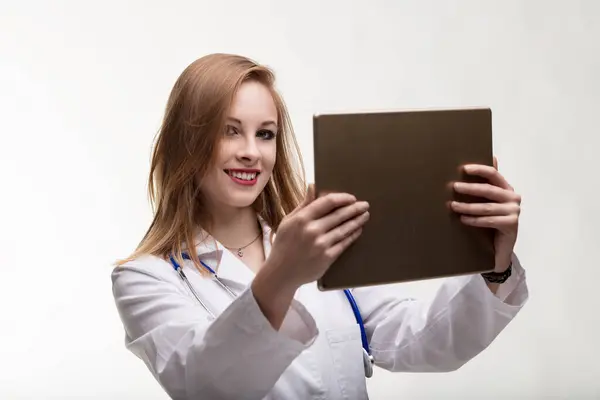 Engaged and tech-savvy doctor reviews patient information on a digital device, smiling