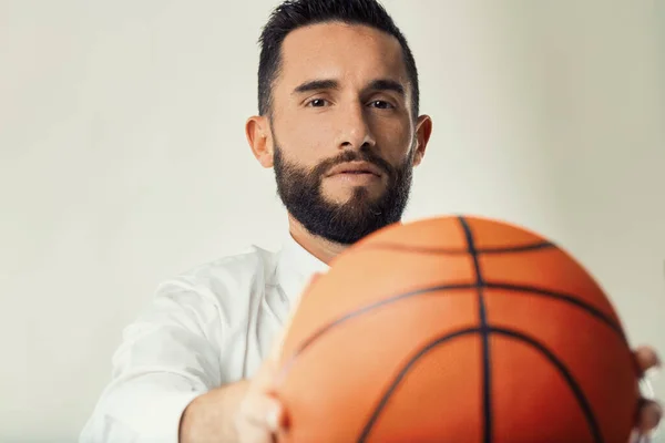 Business professional holds a basketball, illustrating the intersection of sports and corporate strategy