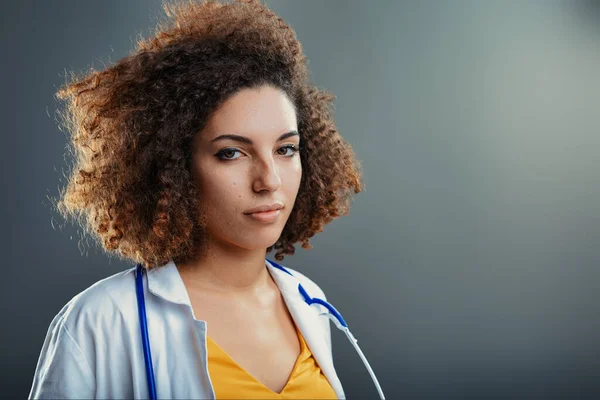 Kıvırcık Saçlı Doktor Klinik Kıyafetli Sabit Bakışlarında Ince Bir Kararlılık — Stok fotoğraf