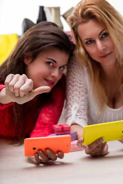 stock image One friend points playfully at the camera, both enjoying a sociable moment with their phones