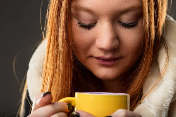 The warmth of the mug is mirrored in the woman\'s gaze, suggesting reflection and comfort