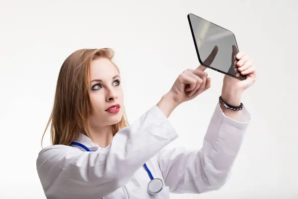 Young medic examines futuristic transparent tablet, curiosity and intelligence in her eyes