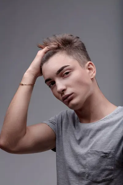 stock image Fashion-forward young individual showcases a trendsetting hairdo and a minimalist fashion sense, hand brushing hair