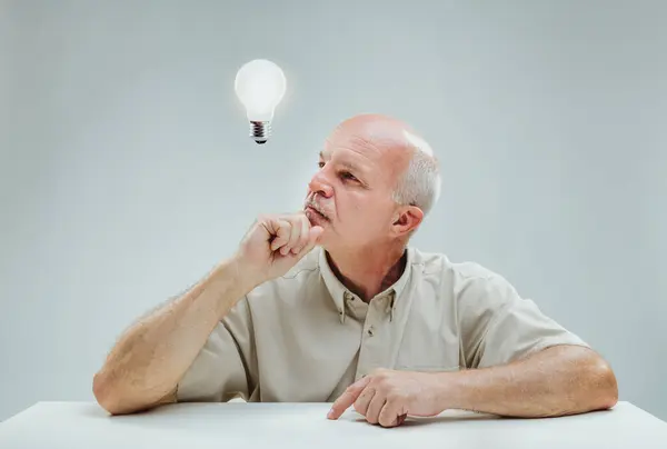 Contemplative Mature Male Gazes Illuminated Bulb Overhead Signifying Moment Inspiration — Stock Photo, Image