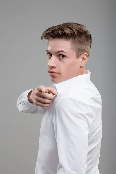 Over-the-shoulder glance reveals young man's confidence and modern style in white shirt, looking back
