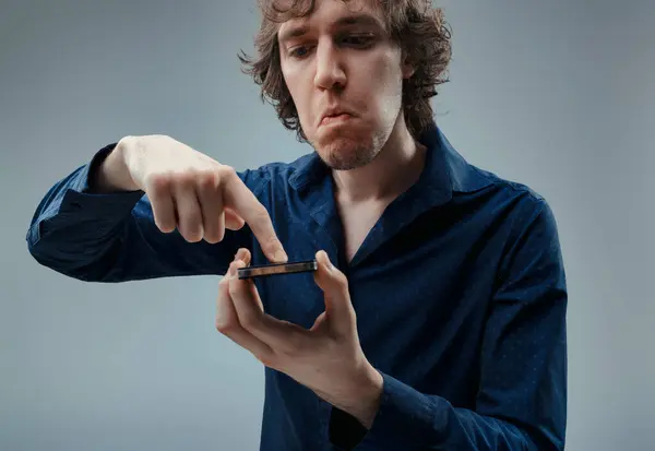 Young Man Curly Hair Examines Phone Evident Distrust His Furrowed — Stock Photo, Image