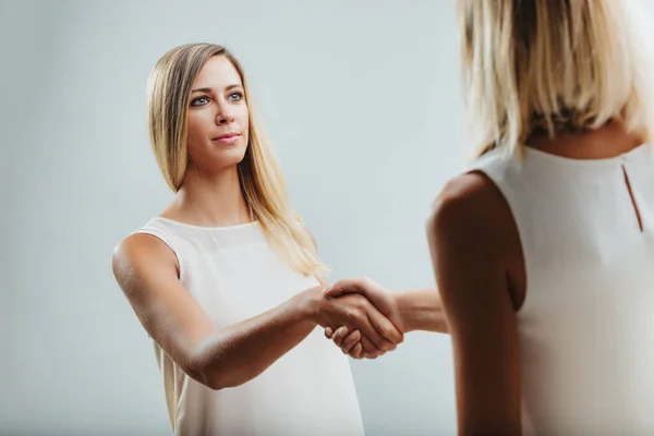 stock image Strong eye contact and a firm handshake communicate the blonde woman's assertive presence