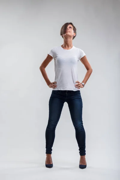 Woman in casual chic attire looks upwards, embodying confidence and determination in her stance