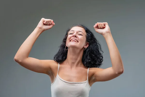 女性は勝利のジェスチャーで彼女の腕を上げ 純粋な喜びの表示で頭を傾けました — ストック写真