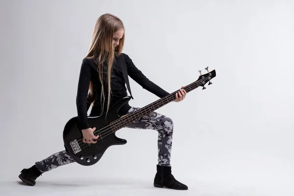 Youthful musician holds a bass guitar, stance exuding confidence and a rock or metal spirit