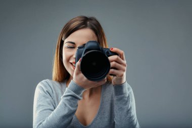 woman's eyes, narrowed in concentration, harmonize with her camera, awaiting the decisive moment clipart