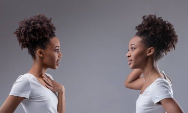 Exchange of whispers between a black woman and her reflection, indulging in the joy of gossip clipart