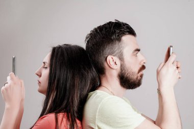 Despite physical closeness, a man and woman focus solely on their smartphones, symbolizing the paradox of connection and isolation in the digital age clipart