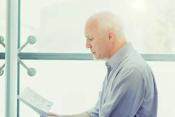 stock image Thoughtful senior examines crucial end-of-life planning papers, considering his future health and retirement strategies in a serene setting