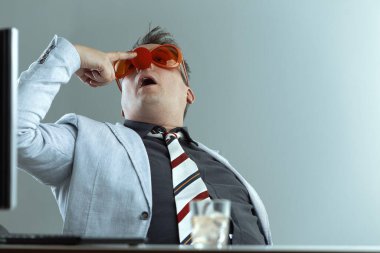 With oversized orange glasses and a red clown nose, the man in a light suit and striped tie holds a whiskey glass. His silly appearance emphasizes the absurdity of workplace drinking clipart