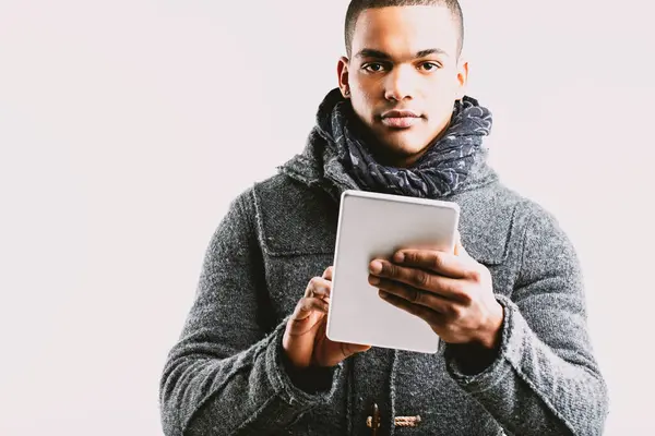 stock image Individual in a grey wool coat and blue scarf, attentively engaging with a digital tablet. His focused expression reflects a preference for informed knowledge over uninformed belief