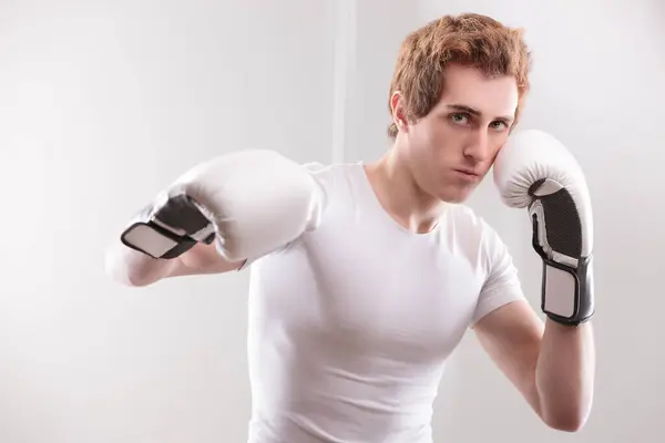 stock image White male boxer in white, geared up with boxing gloves, stands poised for action, embodying strength and focus