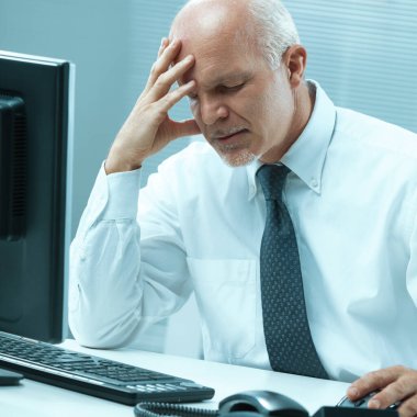 Exhausted executive holds his head, overwhelmed by potential physical discomfort or the psychological impact of realizing a significant blunder clipart