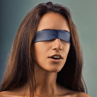 Studio portrait of a young woman wearing a blindfold, expressing feelings of vulnerability, uncertainty, and disorientation as she navigates an unseen world clipart