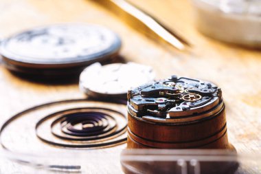 Close-up of watch mechanism with exposed gears and balance spring on a watchmaker's bench. Delicate components reveal the intricate details essential in watchmaking and precise timekeeping clipart