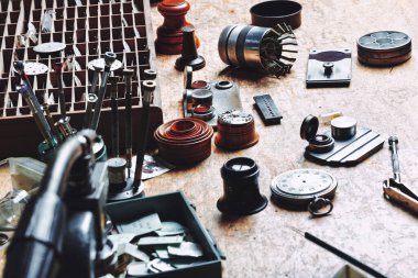 Workbench filled with watch parts and tools, including dials, screwdrivers, and magnifiers. Each tool has a place, reflecting the detailed organization required in watchmaking clipart