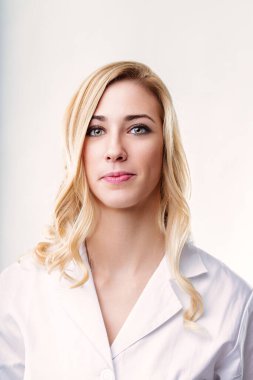 Young female doctor with blond hair, wearing a white lab coat, looking confidently at the camera in a studio setting with a clean white background clipart