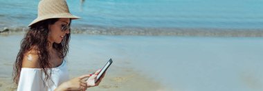 Genç kadın sahilde dijital tablet kullanma