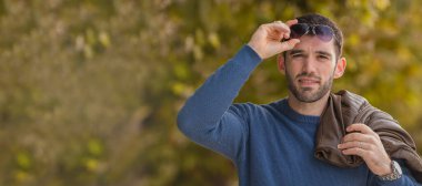 Sonbaharda güneş gözlüklü ve ceketli bir adamın portresi.