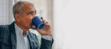 Evde ya da ofiste kahve içen orta yaşlı rahat bir adam.