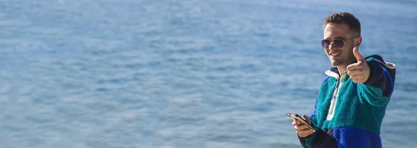 Молодий Чоловік Зимовим Одягом Пляжі Мобільним Телефоном Або Смартфоном — стокове фото