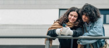 Sokakta cep telefonuna bakan çok ırklı genç bir çift.