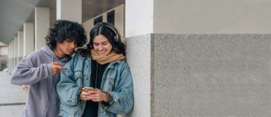 Sokak duvarında cep telefonu olan genç insanlar ve kopyalama alanı