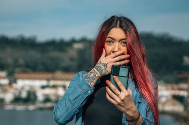 Şaşırmış ifadesi ve cep telefonu olan genç bir kız.