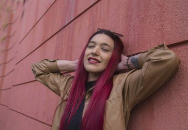 Rahatlamış kızıl saçlı kadın duvara yaslanıyor.