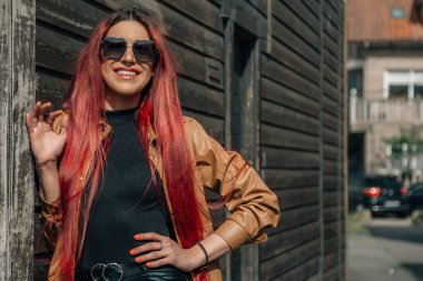 Duvarında bej rengi deri ceketi olan genç bir kadın.