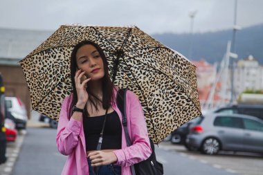 Şemsiyeli ve telefonlu genç kız.