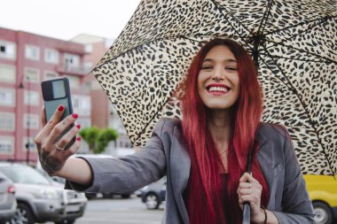 Şemsiyeli ve cep telefonlu etkili kız canlı video çekiyor.