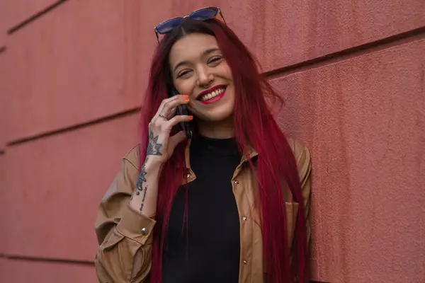Uśmiechnięta Hipsterka Długimi Włosami Telefonem Komórkowym Czerwonym Tle — Zdjęcie stockowe