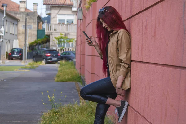 Улыбающаяся Модная Хипстерша Длинными Волосами Мобильным Телефоном Красном Фоне — стоковое фото