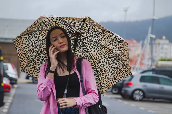 Şemsiyeli ve telefonlu genç kız.