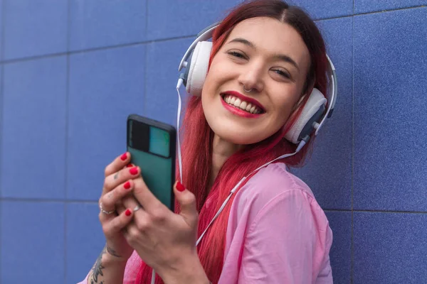 Mujer Joven Sonriente Con Auriculares Teléfono Pared Azul —  Fotos de Stock