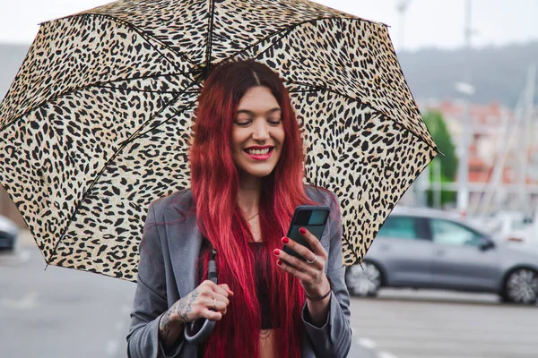 雨の中傘と携帯電話を持った女の子が — ストック写真