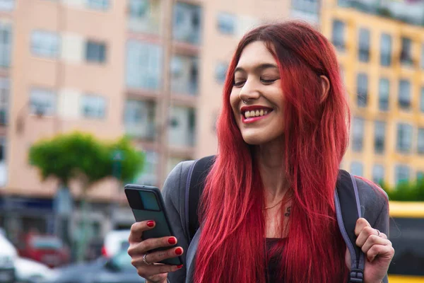 幸せな赤毛の観光客の女の子ですバックパックと電話を街中に — ストック写真