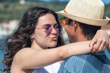 Genç çift sevgiyle sarılıp öpüşüyor dışarıda.