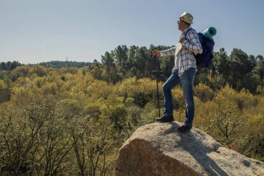 Olgun erkek turist dağın tepesinde manzarayı seyrediyor.