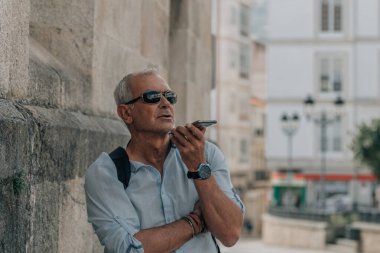 Olgun bir adam telefonla ses veya ses mesajı gönderiyor.