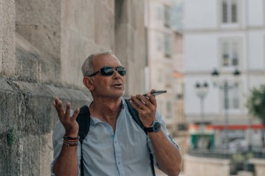 Olgun bir adam telefonla ses veya ses mesajı gönderiyor.