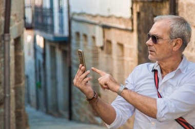 Şehirde cep telefonu olan olgun bir turist.