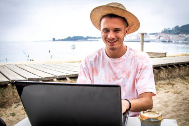Kumsalda dizüstü bilgisayarlı bir turist.
